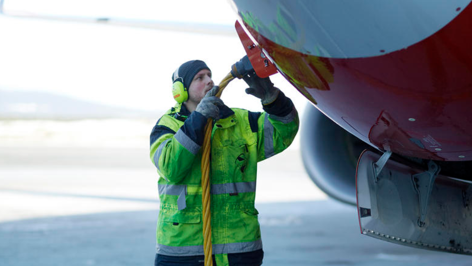 Mann som fyller drivstoff på fly.